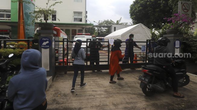 Warga menanyakan informasi tentang pelayanan kepada petugas di Puskesmas Duren Sawit, Jakarta Timur, Rabu (6/1/2021). [Suara.com/Angga Budhiyanto]