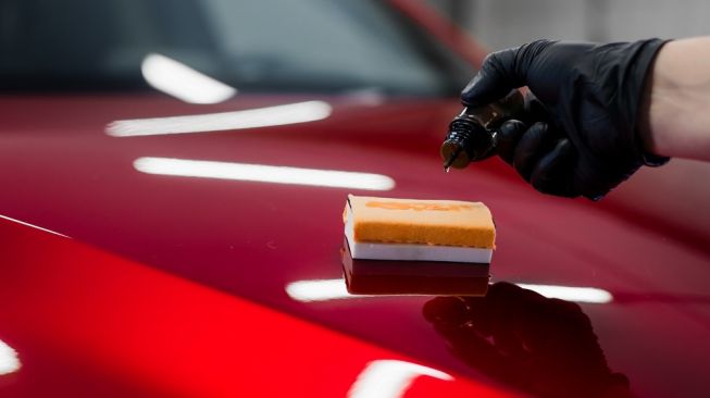 Meneteskan nano protective coating atau wax untuk dioles ke body mobil pada waktu pemolesan [Envato Elements/romankosolapov].