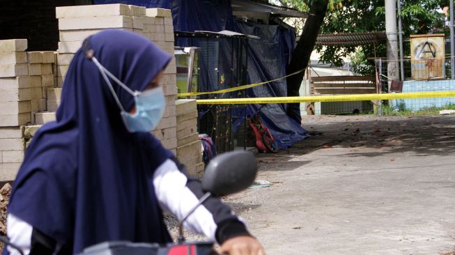 Warga menaiki sepeda motor di dekat rumah terduga teroris yang dipasangi garis polisi usai penggerebekan di Perumahan Villa Mutiara, Kelurahan Bulurokeng, Kecamatan Biringkanaya, Makassar, Sulawesi Selatan, Rabu (6/1/2021). [ANTARA FOTO/Arnas Padda]
