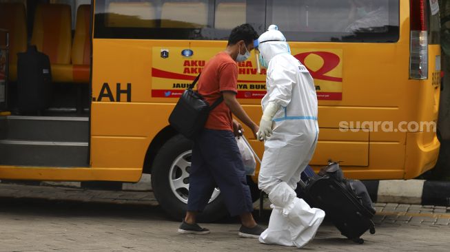 Petugas membantu membawa barang bawaan pasien COVID-19 di Puskesmas Duren Sawit, Jakarta Timur, Rabu (6/1/2021). [Suara.com/Angga Budhiyanto]