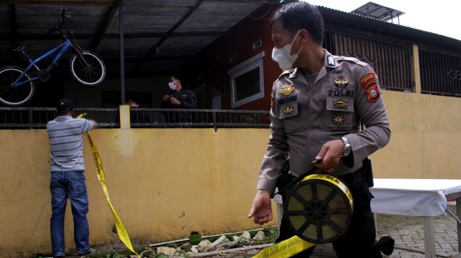 Anggota polisi memasang garis polisi saat menutup akses menuju rumah terduga teroris usai penggerebekan di Perumahan Villa Mutiara, Kelurahan Bulurokeng, Kecamatan Biringkanaya, Makassar, Sulawesi Selatan, Rabu (6/1/2021).  [ANTARA FOTO/Arnas Padda]