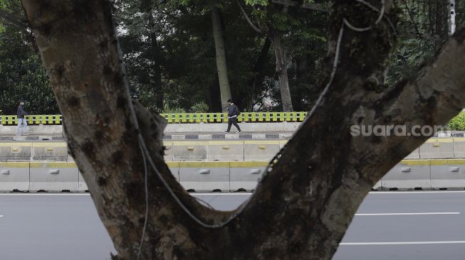 Pekerja berjalan di kawasan Dukuh Atas, Jakarta, Rabu (6/1/2021). [Suara.com/Angga Budhiyanto]