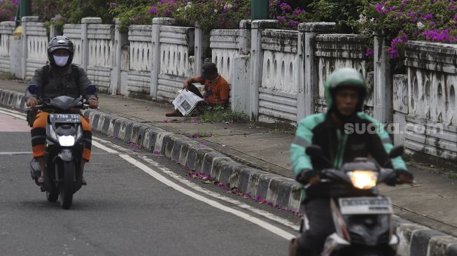 Penyandang Masalah Kesejahteraan Sosial (PMKS) membaca koran di kawasan Kuningan, Jakarta, Kamis (7/1/2021). [Suara.com/Angga Budhiyanto]