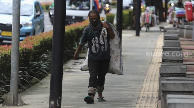 Penyandang Masalah Kesejahteraan Sosial (PMKS) berjalan di kawasan Kuningan, Jakarta, Kamis (7/1/2021). [Suara.com/Angga Budhiyanto]