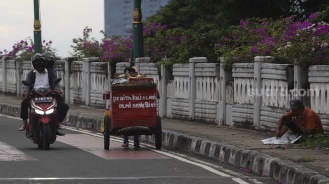 Penyandang Masalah Kesejahteraan Sosial (PMKS) membawa gerobak berjalan di kawasan Kuningan, Jakarta, Kamis (7/1/2021). [Suara.com/Angga Budhiyanto]