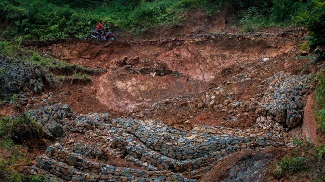 Warga menggunakan kendaraan roda dua melintas di jalan yang longsor di Desa Citorek Kidul, Lebak, Banten, Jumat (8/1/2021).  ANTARA FOTO/Muhammad Bagus Khoirunas