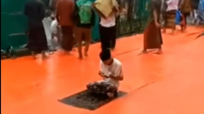 Seorang pria viral karena tetap bertahan di bawah guyuran hujan saat sedang salat.