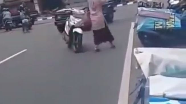 Ibu-ibu memarkir motor di tengah jalan raya