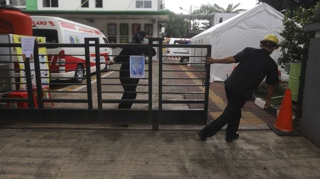 Petugas menutup pagar di Puskesmas Duren Sawit, Jakarta Timur, Rabu (6/1/2021). Menurut petugas, pelayanan umum di Puskesmas Duren Sawit sementara ditutup dari tanggal 4-6 Januari 2021 karena 13 tenaga medis terpapar COVID-19, tapi untuk pelayanan tes usap (swab) tetap dibuka. [Suara.com/Angga Budhiyanto]
