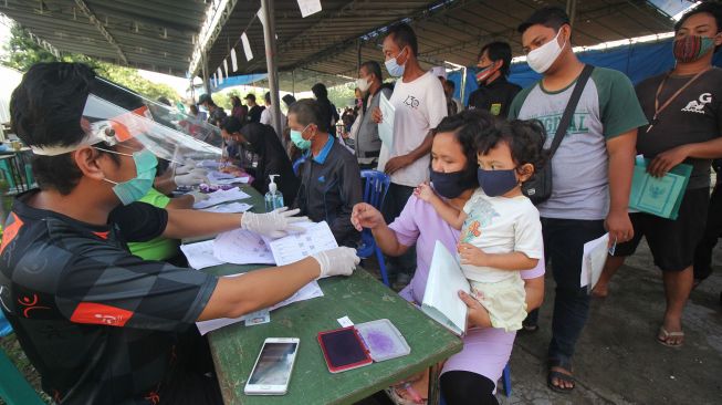 Petugas melayani warga penerima Bantuan Sosial Tunai (BST) di Lapangan Pacar Keling, Surabaya, Jawa Timur, Sabtu (9/1/2021). [ANTARA FOTO/Didik Suhartono]