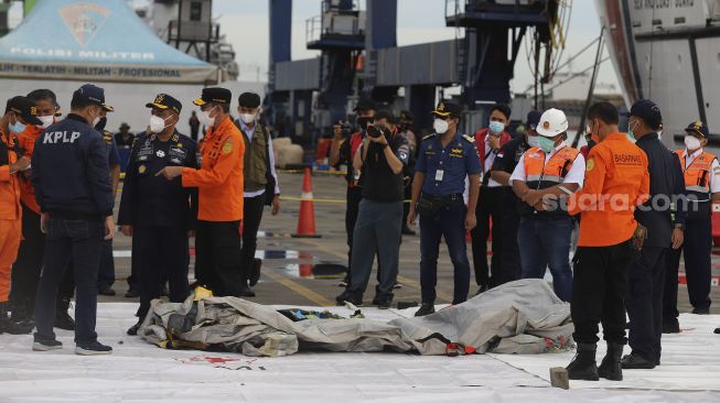 Petugas Kesatuan Penjagaan Laut dan Pantai (KPLP) membawa benda yang diduga serpihan dari pesawat Sriwijaya Air SJ 182 rute Jakarta-Pontianak yang hilang kontak dan jatuh di perairan Kepulauan Seribu, di Dermaga JICT, Jakarta, Minggu (10/1/2021). [Suara.com/Angga Budhiyanto]