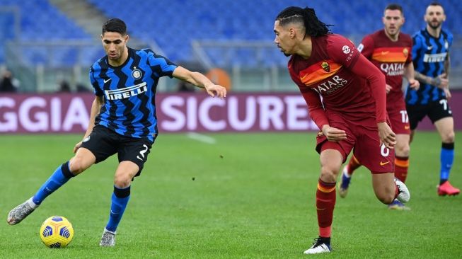 Wing-back Inter Milan, Achraf Hakimi (kiri) menguasai bola dan dibayangi bek AS Roma, Chris Smalling pada laga Liga Italia 2020/2021 di Stadio Olimpico, Roma, Minggu (10/1/2021) malam WIB. [Vincenzo PINTO / AFP]