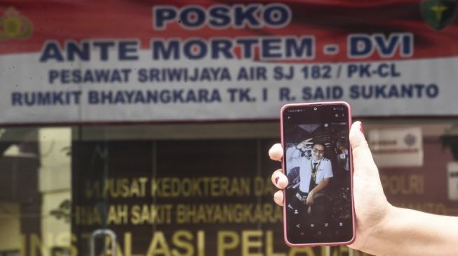 Keluarga Co Pilot pesawat Sriwijaya Air SJ 182 Diego Enrile Mamahit menunjukkan foto diri kru pesawat tersebut di tempat penyerahan data ante mortem guna keperluan identifikasi di RS Polri, Jakarta, Minggu (10/1/2021). [ANTARA FOTO/Muhammad Adimaja]