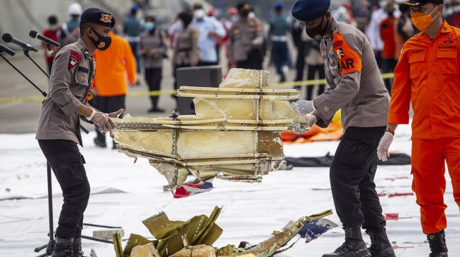 Polisi membawa bagian pesawat Sriwijaya Air SJ182 rute Jakarta - Pontianak yang jatuh di perairan Pulau Seribu di Dermaga JICT, Tanjung Priok, Jakarta Utara, Minggu (10/1/2021). [ANTARA FOTO/Dhemas Reviyanto]