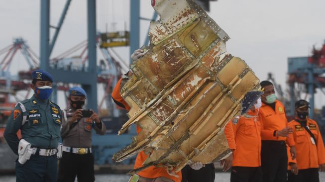 Petugas menata serpihan pesawat Sriwijaya Air SJ 182 rute Jakarta - Pontianak yang jatuh di perairan Pulau Seribu, di Dermaga JICT, Jakarta, Senin (11/1/2021). [ANTARA FOTO/Akbar Nugroho Gumay]
