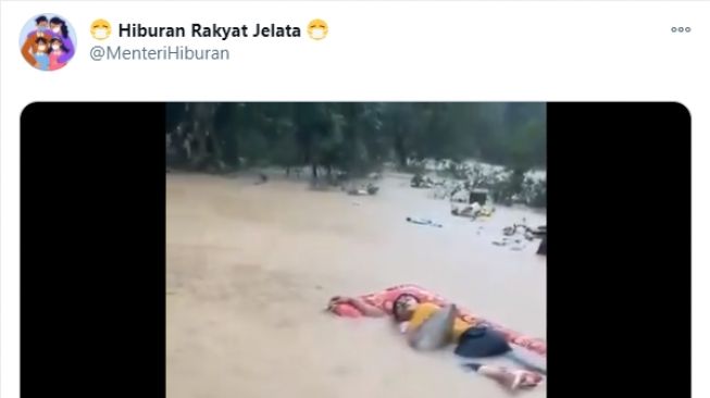 Video seorang pria tertidur lelap di tengah banjir. - (Twitter/@MenteriHiburan)