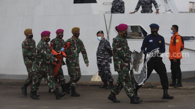 Prajurit TNI Angkatan Darat membawa kantong jenazah berisi bagian tubuh korban dan serpihan pesawat Sriwijaya Air SJ 182 rute Jakarta - Pontianak yang hilang kontak di perairan Kepulauan Seribu, di Dermaga JICT, Tanjung Priok, Jakarta, Senin (11/1/2021). [Suara.com/Angga Budhiyanto]