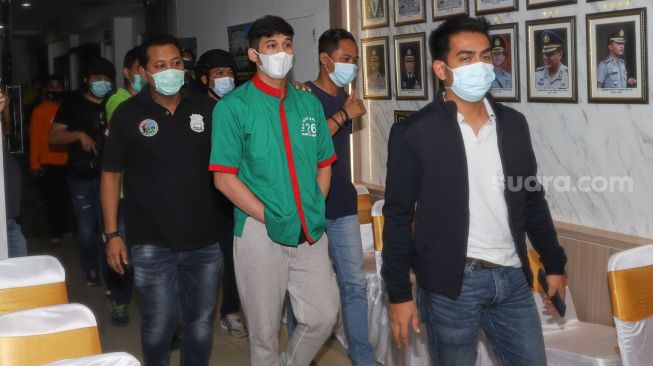 Suami dari Penyanyi Nindy Ayunda, Askara Parasady Harsono saat berjalan menuju ruang konferensi pers sebagai tersangka kasus penyalahgunaan narkoba di Polres Metro Jakarta Barat, Selasa (12/1/2021). [Suara.com/Alfian Winanto]