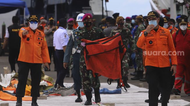 Petugas membawa kantong jenazah korban jatuhnya pesawat Sriwijaya Air SJ 182 rute Jakarta - Pontianak yang hilang kontak di perairan Kepulauan Seribu, di Dermaga JICT, Tanjung Priok, Jakarta, Selasa (12/1/2021). [Suara.com/Angga Budhiyanto]