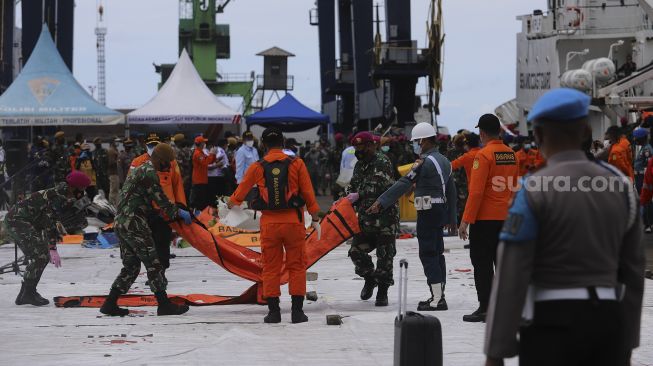 Petugas membawa kantong jenazah korban jatuhnya pesawat Sriwijaya Air SJ 182 rute Jakarta - Pontianak yang hilang kontak di perairan Kepulauan Seribu, di Dermaga JICT, Tanjung Priok, Jakarta, Selasa (12/1/2021). [Suara.com/Angga Budhiyanto]