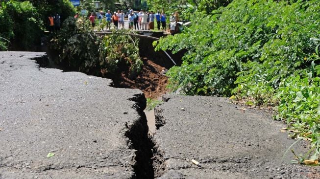 Sejumlah warga menyaksikan lokasi tanah longsor di jalan raya Wonosobo-Kebumen Desa Trimulyo, Wadaslintang, Wonosobo, Jawa Tengah, Selasa (12/1/2021). [ANTARA FOTO/Anis Efizudin]
