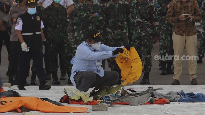 Petugas menata serpihan dan perlengkapan korban pesawat Sriwijaya Air SJ 182 rute Jakarta - Pontianak yang hilang kontak di perairan Kepulauan Seribu, di Dermaga JICT, Tanjung Priok, Jakarta, Selasa (12/1/2021). [Suara.com/Angga Budhiyanto]