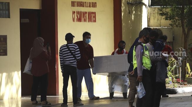 Petugas memindahkan peti mati jenazah  COVID-19 ke dalam mobil ambulans di RS Polri Kramat Jati, Jakarta, Rabu (13/1/2021). [Suara.com/Angga Budhiyanto]