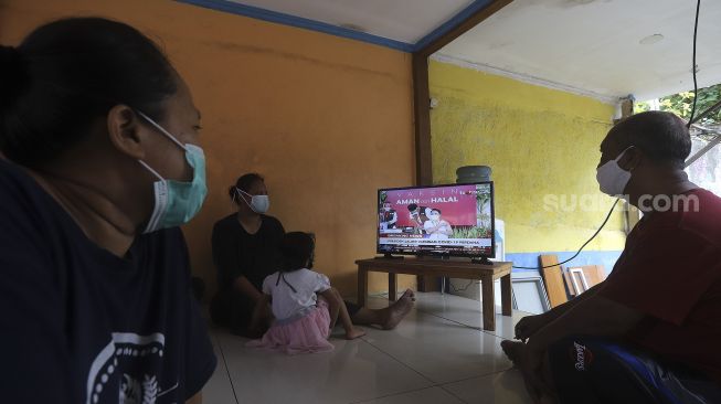 Warga menonton televisi yang menayangkan langsung penyuntikan vaksin CoronaVac perdana di Jakarta, Rabu (13/1/2021). [Suara.com/Angga Budhiyanto]