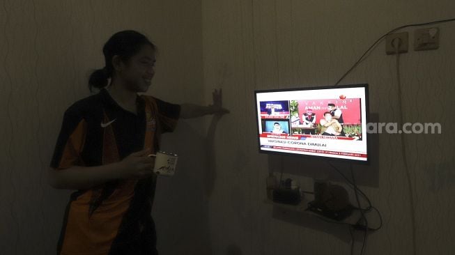 Warga menonton televisi yang menayangkan langsung penyuntikan vaksin CoronaVac perdana di Jakarta, Rabu (13/1/2021). [Suara.com/Angga Budhiyanto]