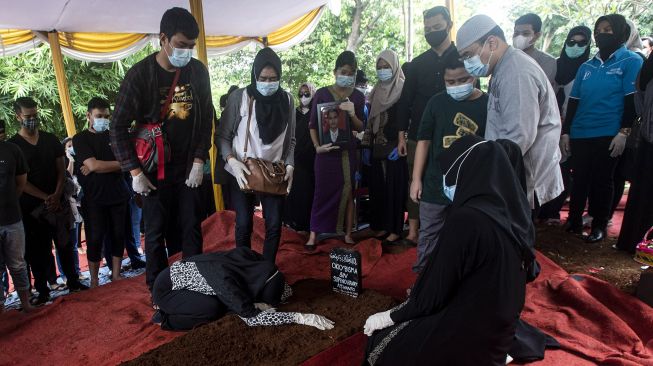 Istri pramugara Okky Bisma, korban kecelakaan Sriwijaya Air SJ 182 rute Jakarta-Pontianak bersujud di pusara suaminya di TPU Balekambang, Jakarta Timur, Kamis (14/1/2021). [ANTARA FOTO/Sigid Kurniawan]