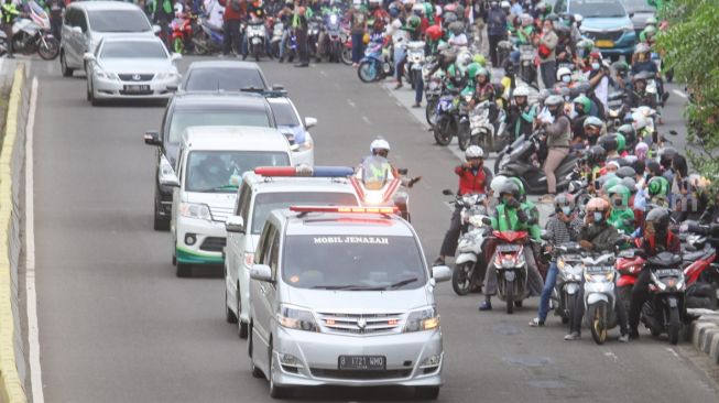 Warga dan pengendara motor melihat Iring - iringan ambulan yang membawa jenazah Syekh Ali Jaber dari Rumah Sakit Yarsi, Cempaka Putih, Jakarta Timur, Kamis (14/1/2021). [Suara.com/Alfian Winanto]