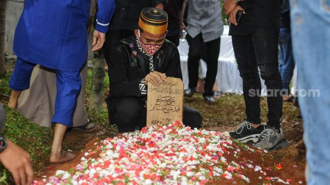 Kerabat dan keluarga berdoa diatas pusara Syekh Ali Jaber setelah dimakamkan di Pesantren Daarul Quran, Tangerang, Banten, Kamis (14/1/2021). [Suara.com/Alfian Winanto]