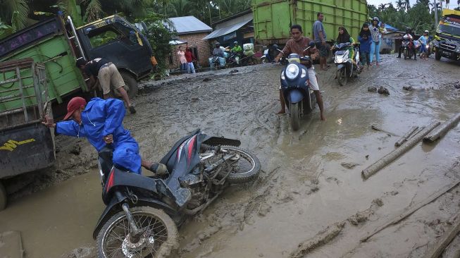 Pengendara motor terjatuh saat melintasi Jalan Lintas Jambi-Nipah Panjang yang rusak di Siau Dalam, Tanjungjabung Timur, Jambi, Rabu (14/1/2021). [ANTARA FOTO/Wahdi Septiawan]