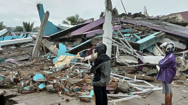 Warga mengamati bangunan RS Mitra Manakarra yang roboh pascagempa bumi, di Mamuju, Sulawesi Barat, Jumat (15/1/2021). [ANTARA FOTO/Akbar Tado]