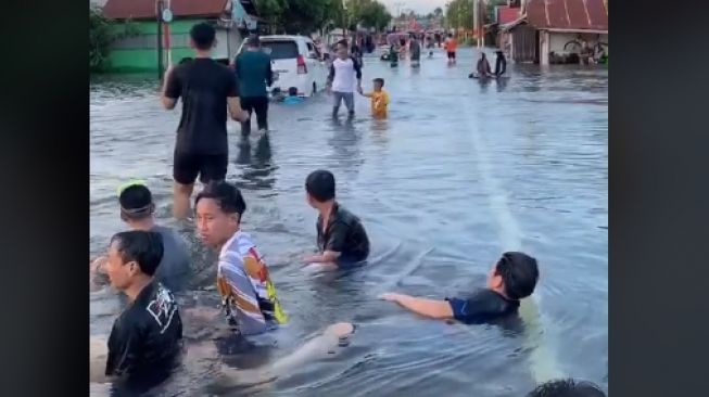 Bak Wahana Wisata, Warga Santai Main Air di Ruas Jalan yang Banjir