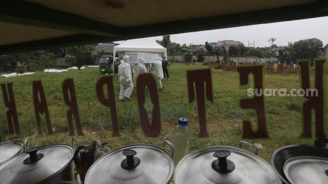 Petugas mengusung peti berisi jenazah yang meninggal dunia karena COVID-19 untuk dimakamkan di TPU Srengseng Sawah, Jakarta, Jumat (15/1/2021). [Suara.com/Angga Budhiyanto]