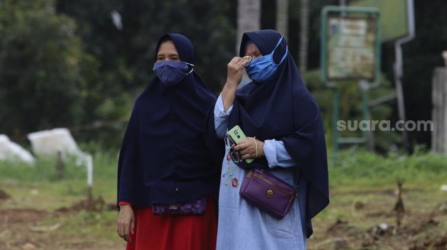 Keluarga melihat proses pemakaman jenazah yang meninggal dunia karena COVID-19 di TPU Srengseng Sawah, Jakarta, Jumat (15/1/2021). [Suara.com/Angga Budhiyanto]