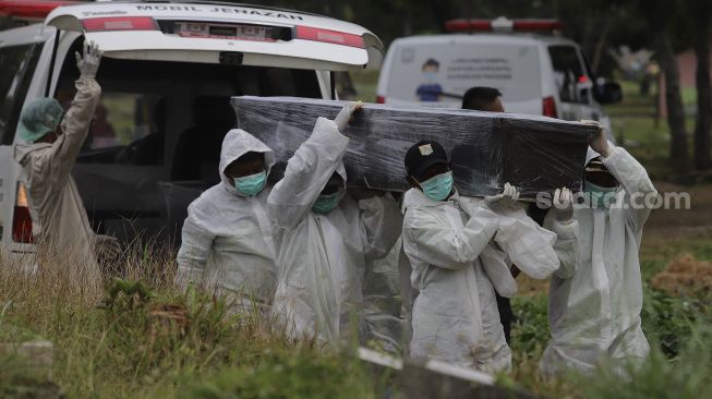 Petugas mengusung peti berisi jenazah yang meninggal dunia karena COVID-19 untuk dimakamkan di TPU Srengseng Sawah, Jakarta, Jumat (15/1/2021). [Suara.com/Angga Budhiyanto]