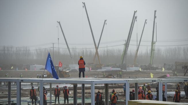 Staf konstruksi bekerja di lokasi konstruksi pusat pengamatan medis terpusat, fasilitas darurat untuk mengisolasi orang-orang yang berisiko tertular Covid-19 di Shijiazhuang, Provinsi Hebei, China utara, pada (15/1/2021). [STR / CNS / AFP]