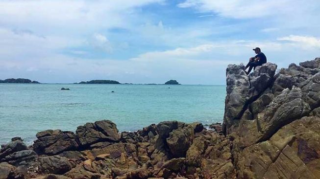 Seseorang sedang menikmati suasana di kawasan pantai di Pulau Jemur, Kabupaten Rokan Hilir yang indah dan menawan dengan pasir putih dan bebatuan. [Suara.com/Panji Ahmad Syuhada]