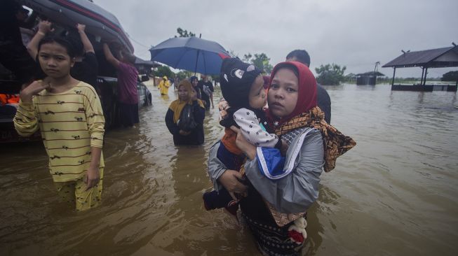 Warga menggendong anaknya melintasi banjir di Desa Kampung Melayu, Kabupaten Banjar, Kalimantan Selatan, Jumat (15/1/2021). [ANTARA FOTO/Bayu Pratama S]