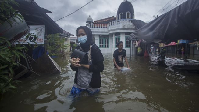 Warga melintasi banjir yang menggenangi kawasan padat penduduk di Kabupaten Banjar, Kalimantan Selatan, Jumat (15/1/2021). [ANTARA FOTO/Bayu Pratama S]