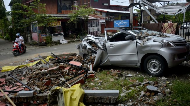 Sebuah mobil rusak terdampak akibat gempa bumi di Kabupaten Mamuju, Sulawesi Barat, Minggu (17/1/2021). [ANTARA FOTO/Abriawan Abhe]
