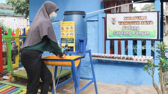 Warga mencuci tangan saat memasuki Kampung Tangguh Jaya di Penggilingan, Cakung, Jakarta Timur, Minggu (17/1/2021). [Suara.com/Alfian Winanto]