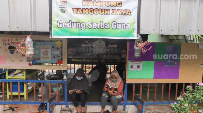 Warga beraktivitas di gedung serba guna Kampung Tangguh Jaya, Penggilingan, Cakung, Jakarta Timur, Minggu (17/1/2021). [Suara.com/Alfian Winanto]