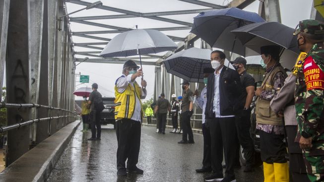 Presiden Joko Widodo (kanan) meninjau langsung lokasi banjir dari atas jembatan Pekauman didampingi Menteri PUPR Basuki Hadimuljono (kiri) di Desa Pekauman Ulu, Kabupaten banjar, Kalimantan Selatan, Senin (18/1/2021).  [ANTARA FOTO/Bayu Pratama]