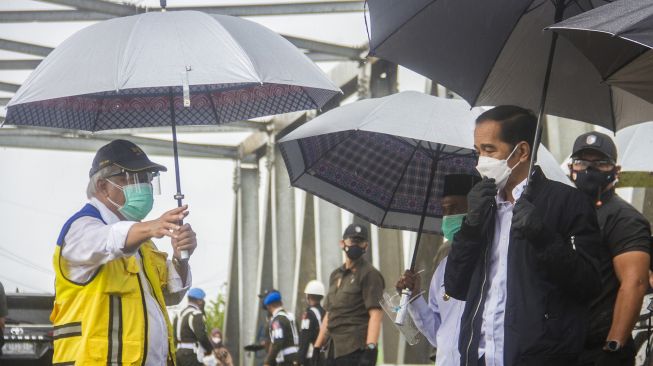 Presiden Joko Widodo (kanan) meninjau langsung lokasi banjir dari atas jembatan Pekauman didampingi Menteri PUPR Basuki Hadimuljono (kiri) di Desa Pekauman Ulu, Kabupaten banjar, Kalimantan Selatan, Senin (18/1/2021).  [ANTARA FOTO/Bayu Pratama]