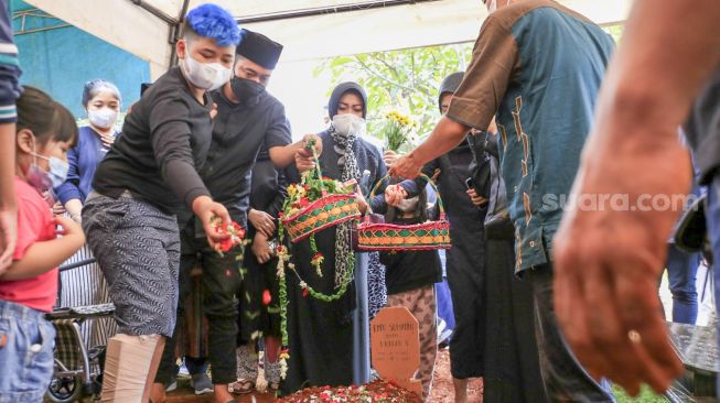 Komedian Denny Cagur dan keluarga menabur bunga diatas pusara ibunya usai dimakamkan di TPU Tipar, Depok, Jawa Barat, Selasa (19/1/2021). [Suara.com/Alfian Winanto]