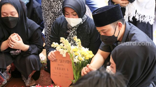 Komedian Denny Cagur berdoa diatas pusara ibunya  setelah dimakamkan di TPU Tipar, Depok, Jawa Barat, Selasa (19/1/2021). [Suara.com/Alfian Winanto]