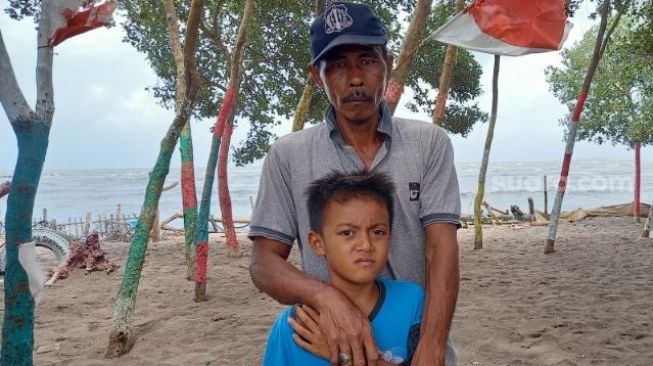 Muhammad Mamat (49) dan keponakannya Angga Satria (8) menemukan tempurung kepala manusia di sekitar Pantai KSS, Pakuhaji, Kabupaten Tangerang, saat ditemui di lokasi, Rabu (20/1/2021). [Suara.com/Muhammad Jehan Nurhakim]